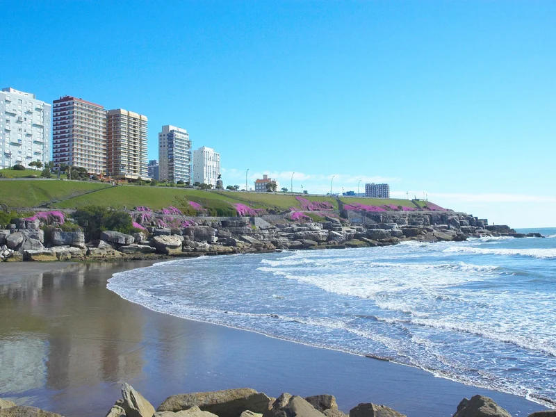 Costa de Mar del Plata con olas, playa y edificios sobre la barranca verde