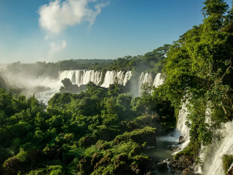 Cataratas del Iguazú cayendo entre la selva bajo cielo azul